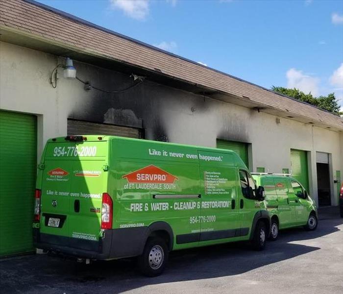 A five car garage building with smoke damage, and SERVPRO vehicles parked in front of the building. 