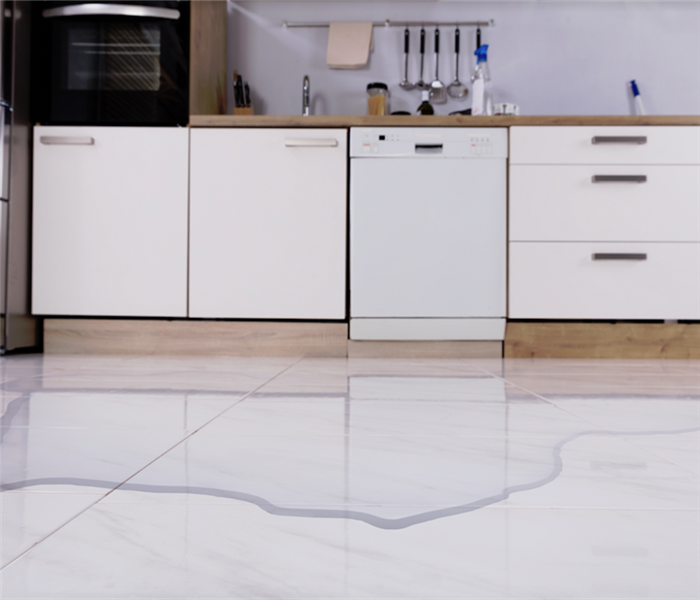 water covering the white tile floor of a kitchen