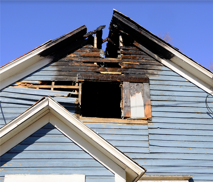 the exterior of a burned house with part of the roof missing and covered in soot